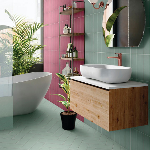Colorful bathroom with light green tile flooring laid in a herringbone pattern, light green and maroon backsplash, floating wood vanity with vessel sink.