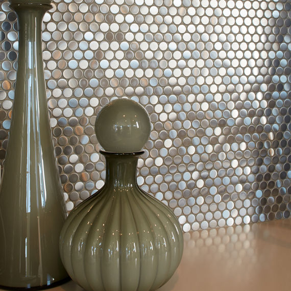 Silver metal look penny round mosaic tile on back wall, beige table top, and two green vases.