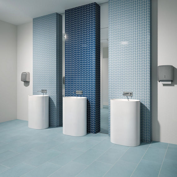 Bathroom with three sinks, blue chevron mosaic tile on backsplash of one sink, and light blue chevron tile on backsplash of other two sinks.