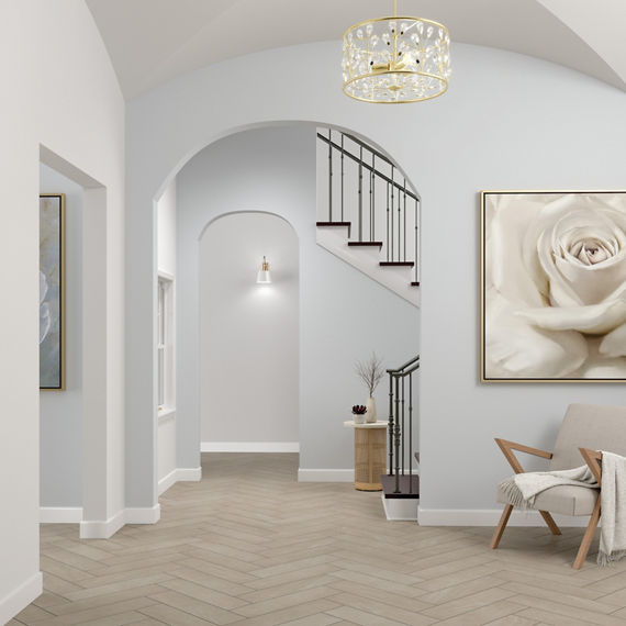Foyer with arched doorways, gray floor tile that looks like stone set in a herringbone pattern, wood chair with off-white cushions.