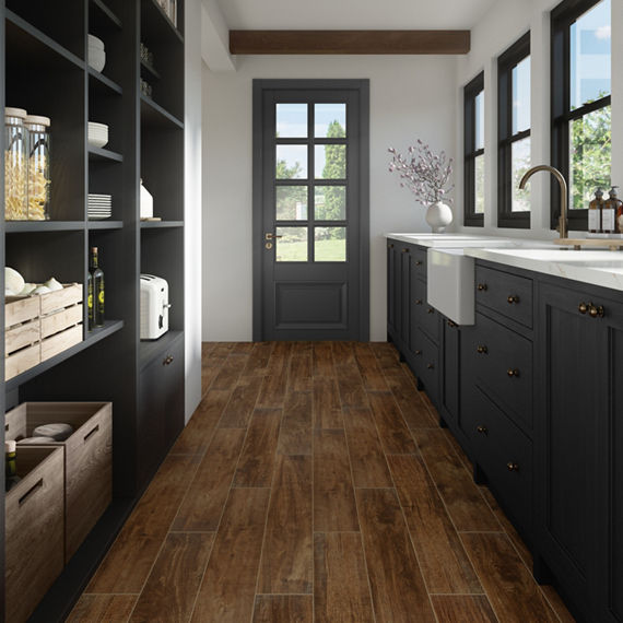 Kitchen with wood look floor tile, black cabinets, white countertop, black shelves, and view of trees through doors and windows.