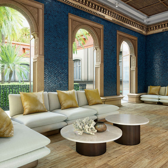 Hotel lobby with blue hexagon wall tile, wood look floor tile, white couches, two round coffee tables, and gold accents.