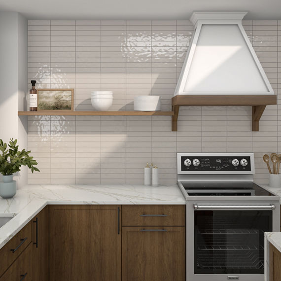 Kitchen with white rectangle subway tile on backsplash in horizontal pattern, wood cabinets, white marble look countertop, and wooden shelf with bowls.