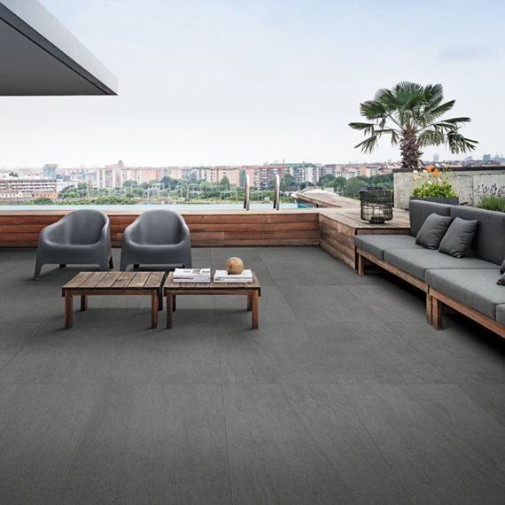 Outdoor patio with gray stone look rectangle floor tile, gray outdoor couches, and wood accents.