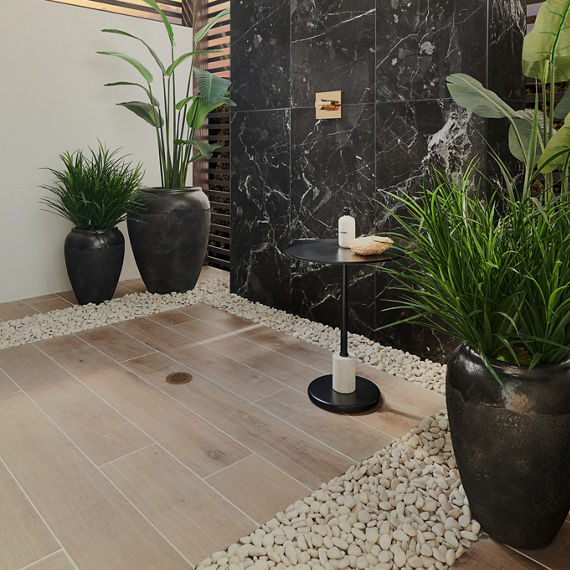 Shower with rectangle wood look plank tile, black marble look rectangle tile on back wall, white walls on side, and greenery in large pots.