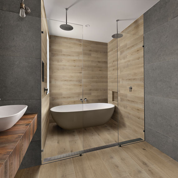 Bathroom with wood planks in shower floor and walls, gray concrete look tile on outside walls, wood countertop, and white double sinks.