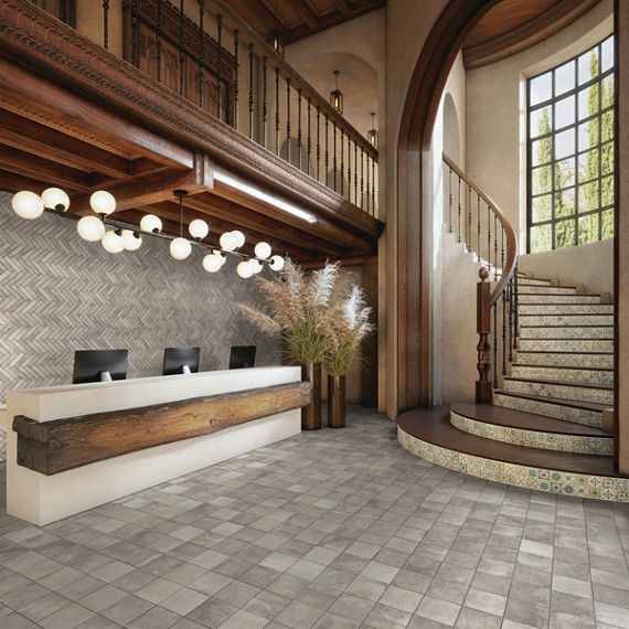 Welcome area with gray square concrete look floor tile, gray rectangle concrete look mosaic in chevron pattern on back wall, and encaustic mosaic tile on stairs.