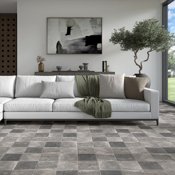 Living room with gray square cotto look floor tile, white couch, small tree, and floor to ceiling window showing the outside.