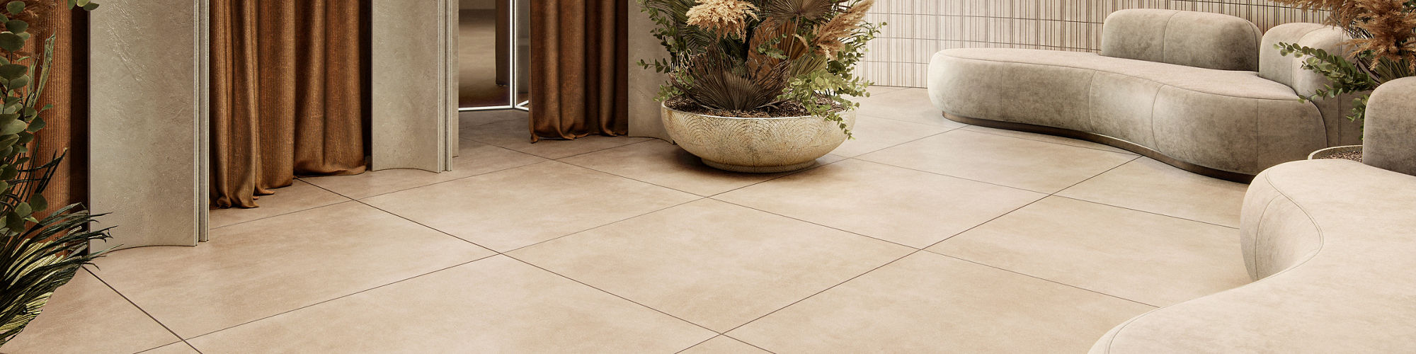 Dressing room waiting area with beige large format square concrete look floor tile, white couches, three dressing rooms with orange curtains, and a large vase with greenery.