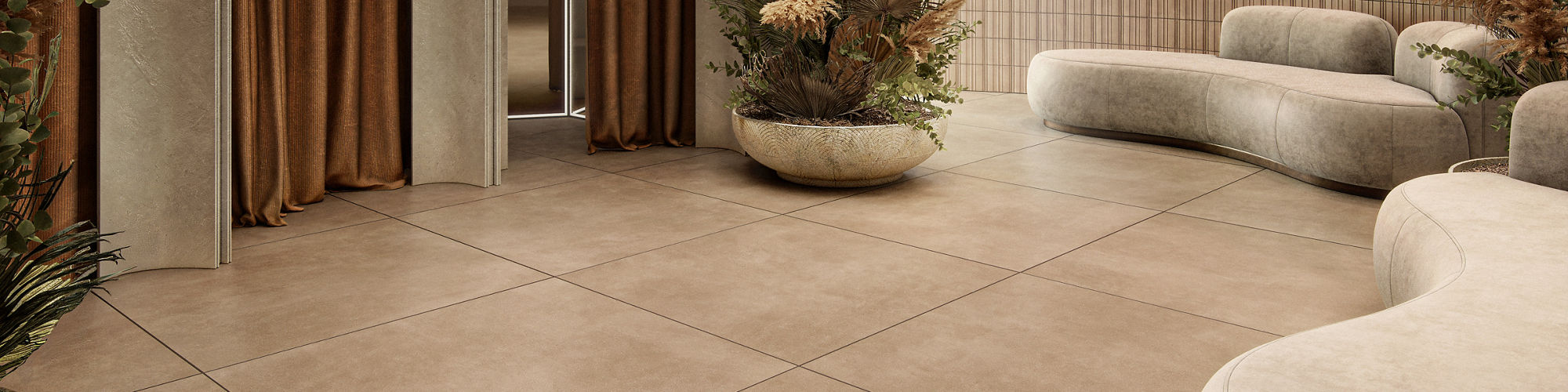Dressing room waiting area with dark beige large format square concrete look floor tile, white couches, three dressing rooms with orange curtains, and a large vase with greenery.
