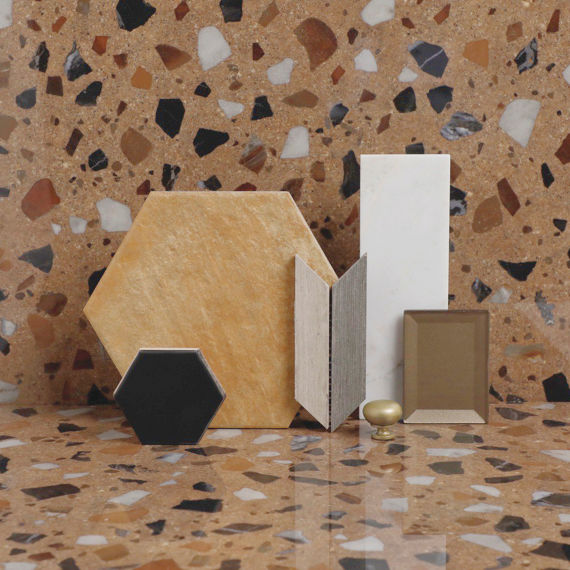 Flatlay with beige terrazzo look tile, orange hexagon cotto look tile, whtie herringbone tile, white subway tile, and small black hexagon tile.
