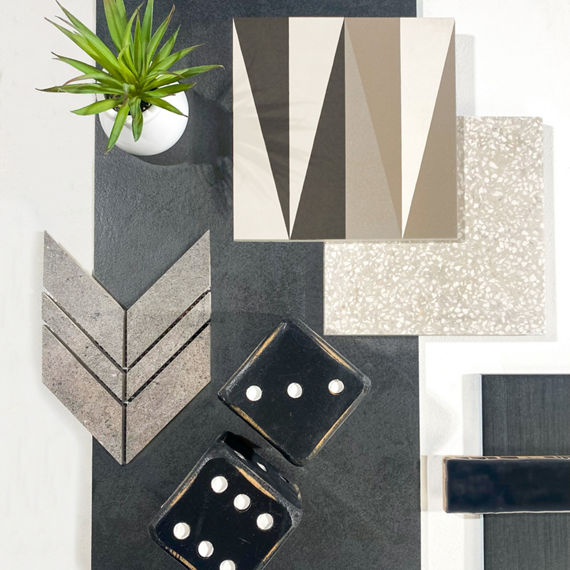This flatlay has black concrete look rectangle tile, white square terrazzo look tile, white encaustic tile, black subway tile, and gray stone look chevron mosaic tile.