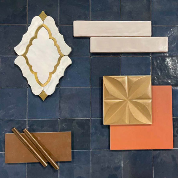 This flatlay contains glass look undulated tile accented with a stone arabesque mosaic tile, undulated accent tile, concrete look tile, and a three dimensional metal accent tile.