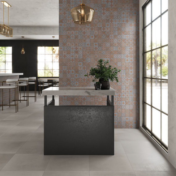 Waiting area with square concrete look tile on back wall, gray square concrete look tile on floor, white counter on standing desk, and gold accents.