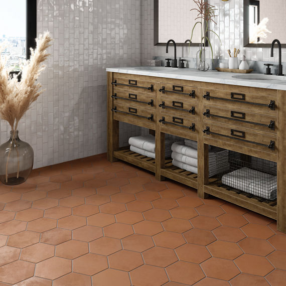 Bathroom with terracotta hexagon floor tile, wood cabinets, and white countertop.