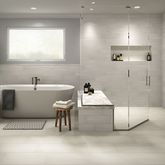 Bathroom with white concrete look rectangle floor tile, white rectangle concrete look tile on walls, white tub, and silver accents.
