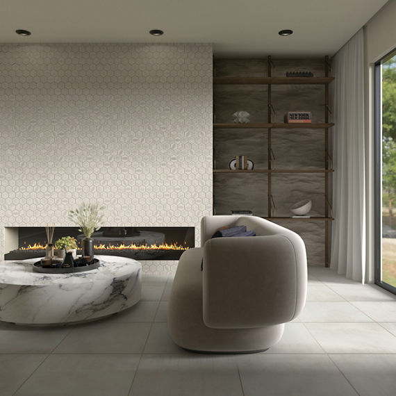 Living room with white monochromatic look hexagon tile on back wall, white square floor tile, round white marble coffee table, and white couch.