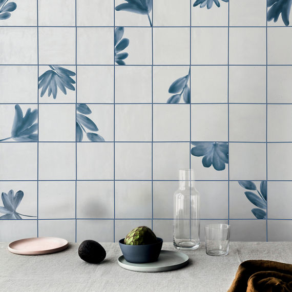 Table top with white encaustic square tile on backsplash, blue grout, and dishes on table.