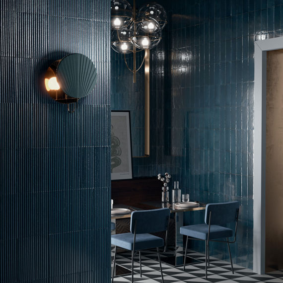 Restaurant with blue subway tile on back walls, blue fluted rectangle tile on side wall, dark dining tables, and blue chairs.
