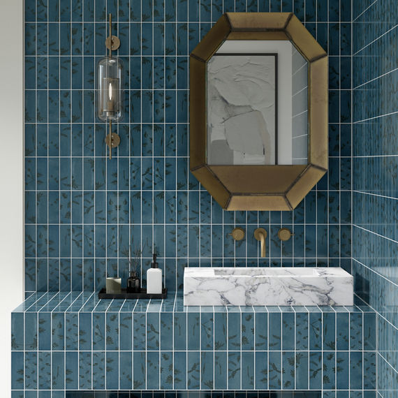 Bathroom with blue rectangle subway tile on back wall and counter, octagon shaped mirror above sink, white marble sink, and white square floor tile.