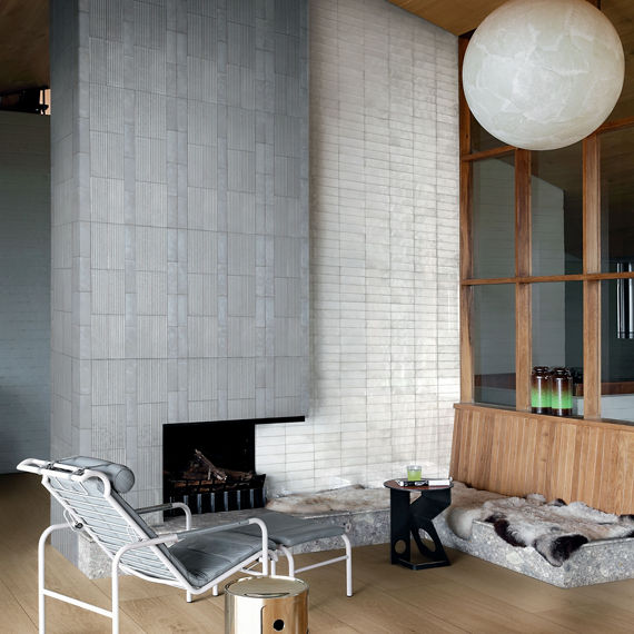 Living room with gray rectangle tile on fireplace surround, white subway tile on back wall, and wood flooring.