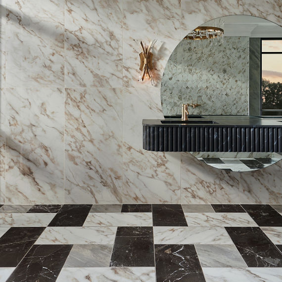 Bathroom with white marble look square tiles on back wall, white rectangle marble look tile on floor, black marble look rectangle tile on floor, gray square marble look tile on floor, and black counter with gold accents.