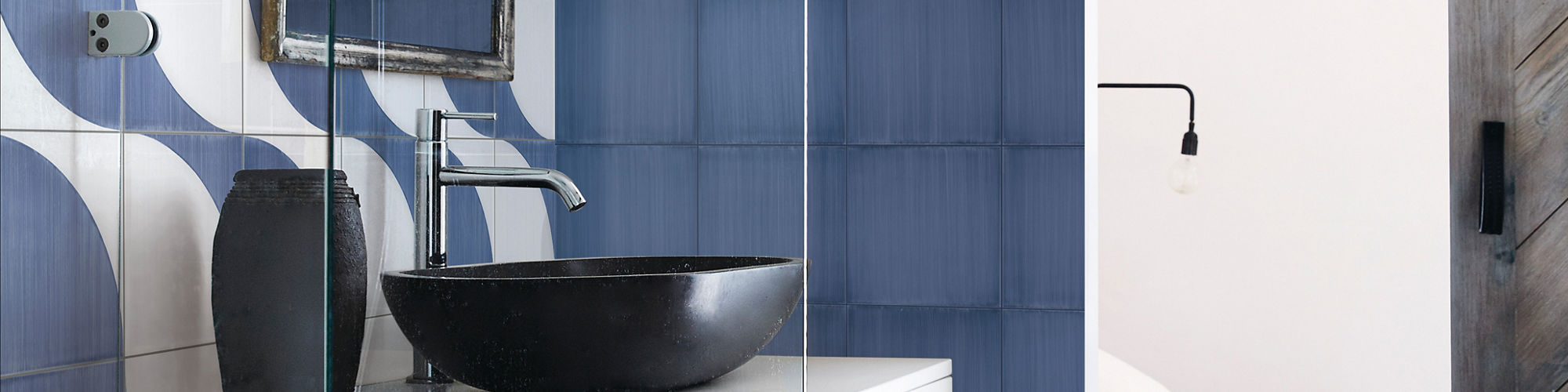 Bathroom with white and blue encaustic concrete look tile on back wall and floor, blue concrete look tile on right wall, and black and white accents.