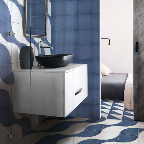 Bathroom with white and blue encaustic concrete look tile on back wall and floor, blue concrete look tile on right wall, and black and white accents.