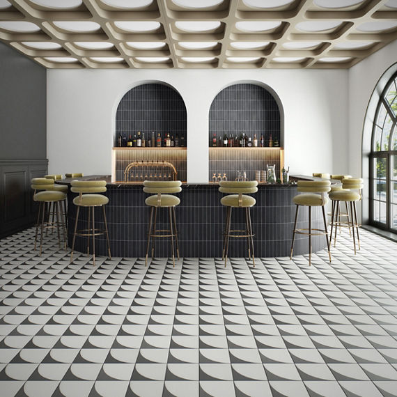 Bar with white walls, white and black square floor tile with concave design, black subway tile on bar counter, and light green chairs at bar.
