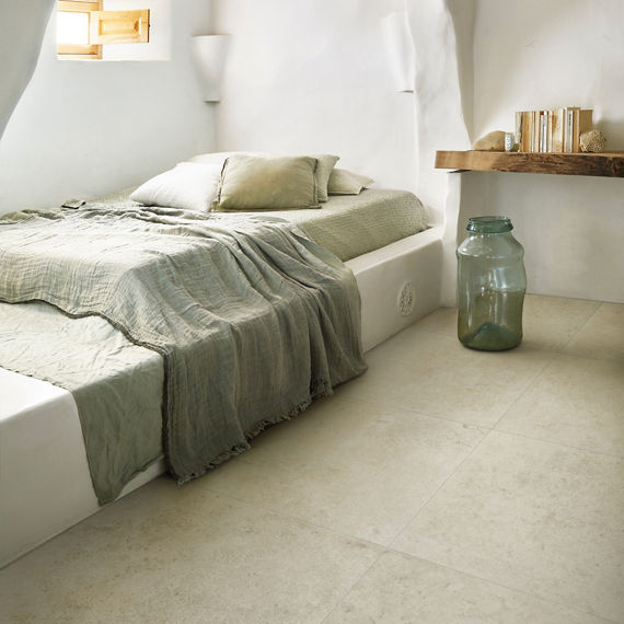Bedroom with white stone look square floor tile, wood shelf with books, and white walls.