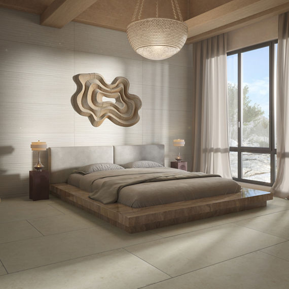 Bedroom with white rectangle tile with linear design on walls, white concrete look rectangle tile on floor, beige bed, and large window showing the outdoors.