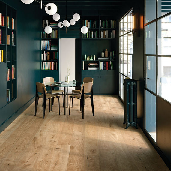 Dining area with wood look tile planks on floor, blue walls, and shelves with books on side and back wall.