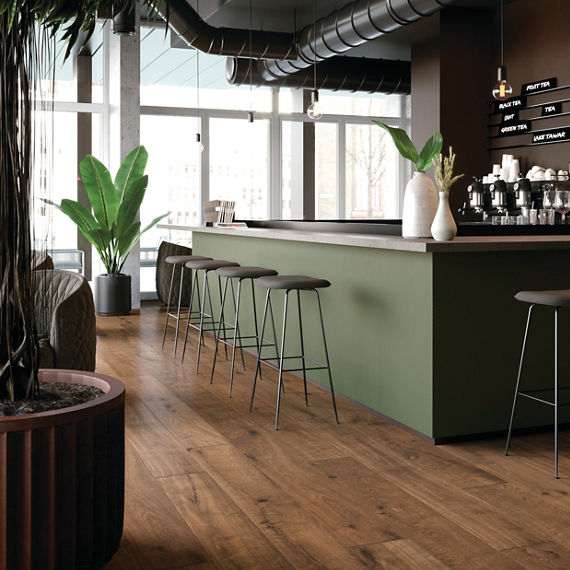 Restaurant with wood look plank floor tile, green counter, gray countertop, and greenery on counter.