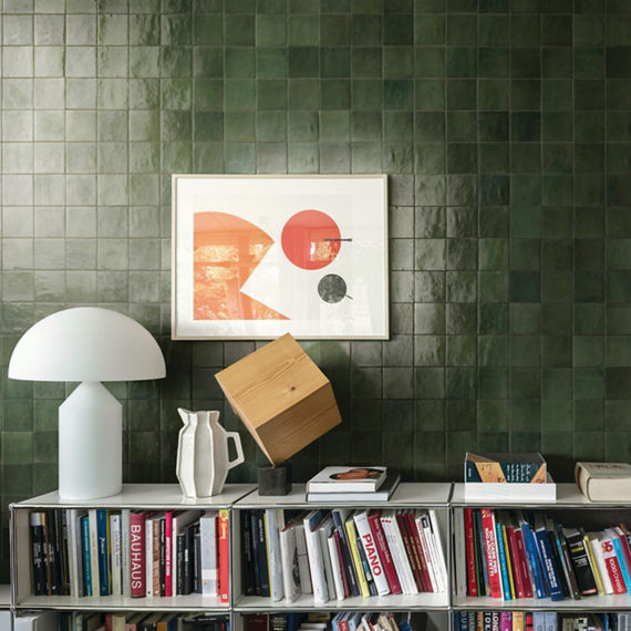 White book shelves with books, green square undulated tile on wall, green grout, and white accents.