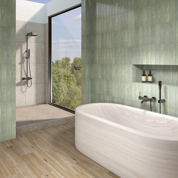 Bathroom with green subway tile on walls, white tub, and light wood flooring.