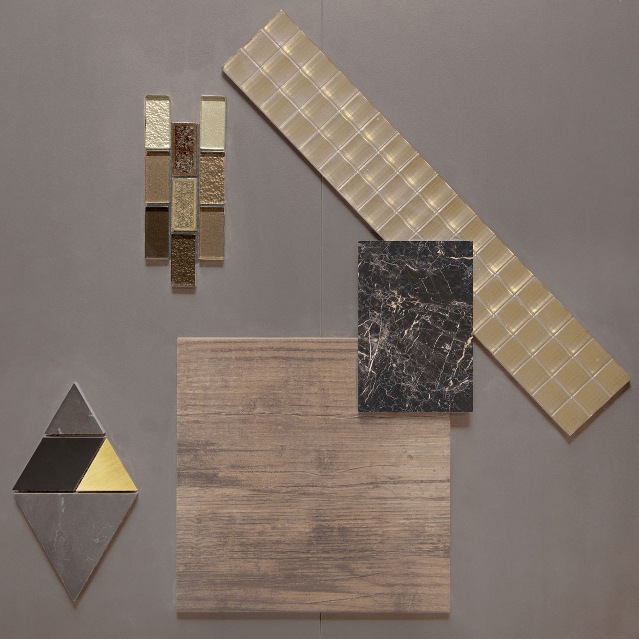 This flatlay contains a concrete look tile accented by a wood tile, marble accent tile, glass mosaic, and a metal diamond accent tile.