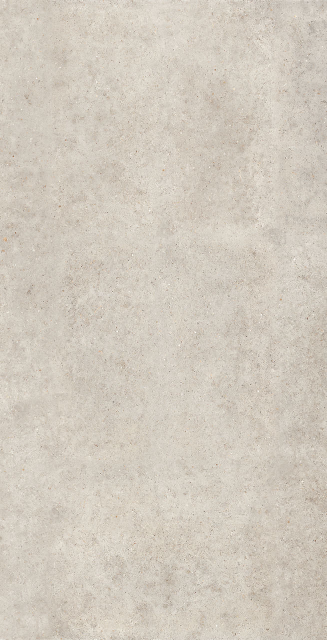 Vertical close-up of a light beige concrete or stone surface with subtle speckled details. The texture appears slightly rough and weathered, with small variations in tone and grain. No objects, people, or text are visible, emphasizing the material pa