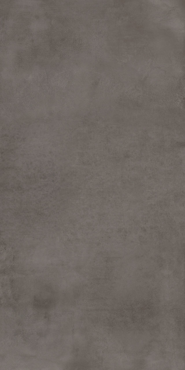 The image features a close-up view of a gray concrete surface with a textured, slightly mottled appearance. The surface displays subtle tonal variations and a matte finish, evoking an industrial or modern aesthetic. No visible text, numbers, or ident