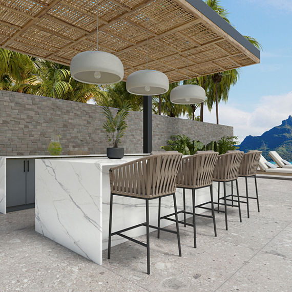 Outdoor bar with wooden sitting stools, white marble look porcelain counter, and a mountain in the background.
