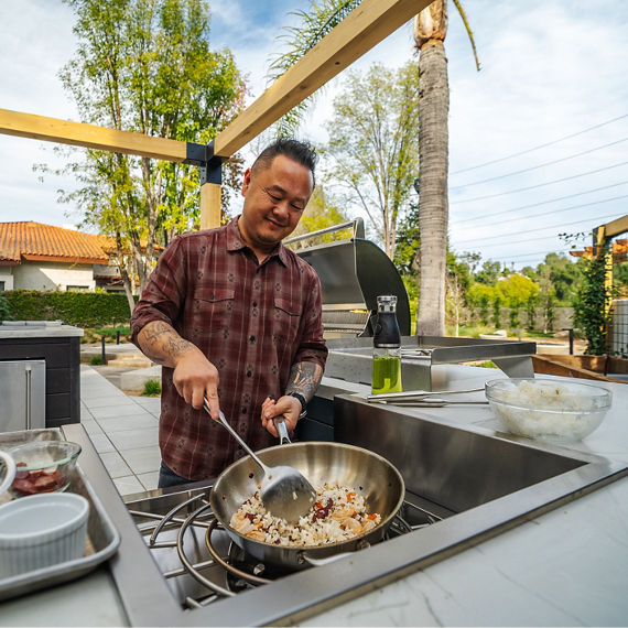 Jet Tile cooking in an outdoor kitchen with beige quartzite countertops.