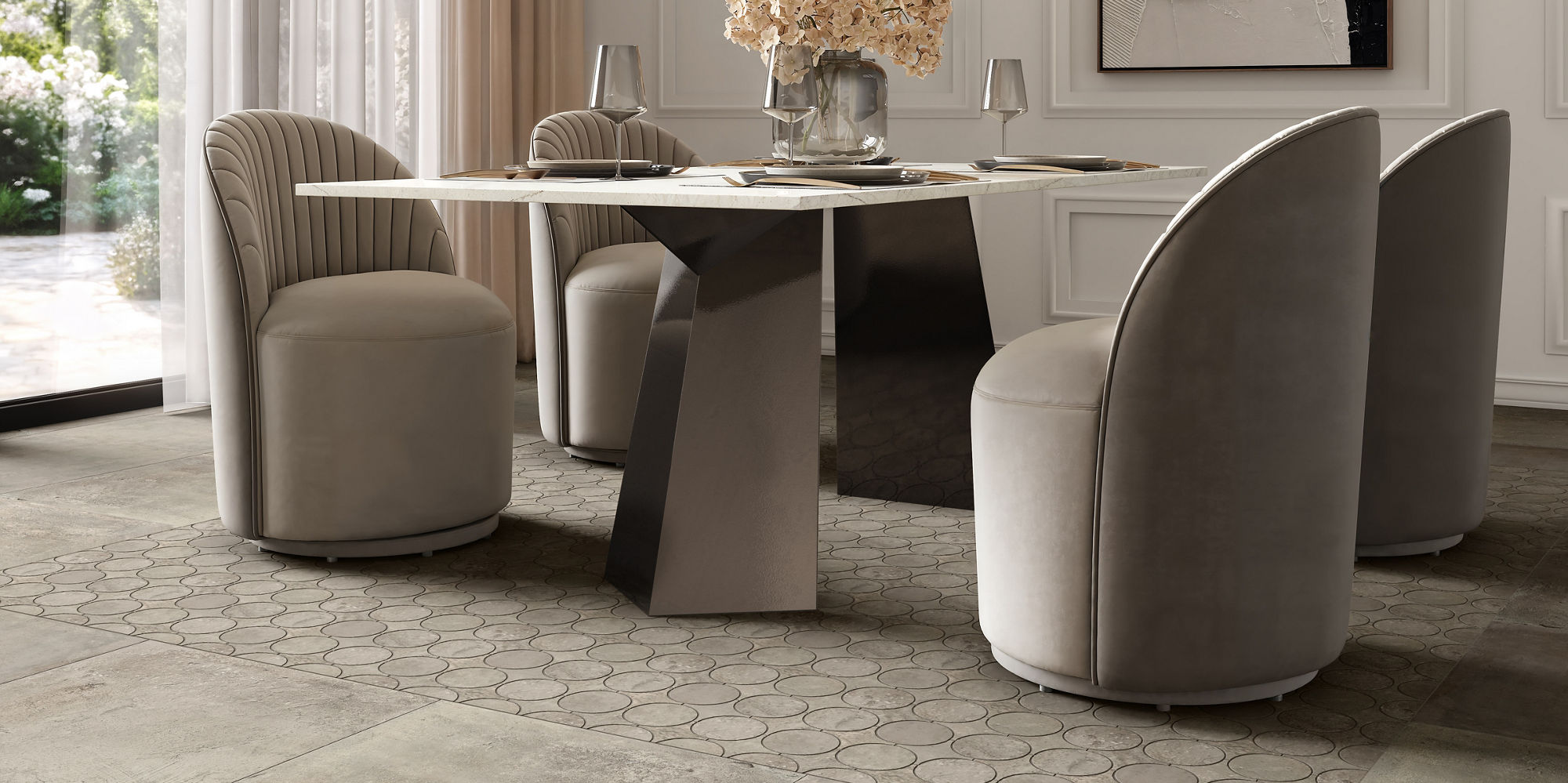 A contemporary dining room features a round table with a sculptural geometric base surrounded by four plush upholstered chairs. Large floor-to-ceiling windows with sheer curtains fill the space with natural light and views of greenery outside. A mode