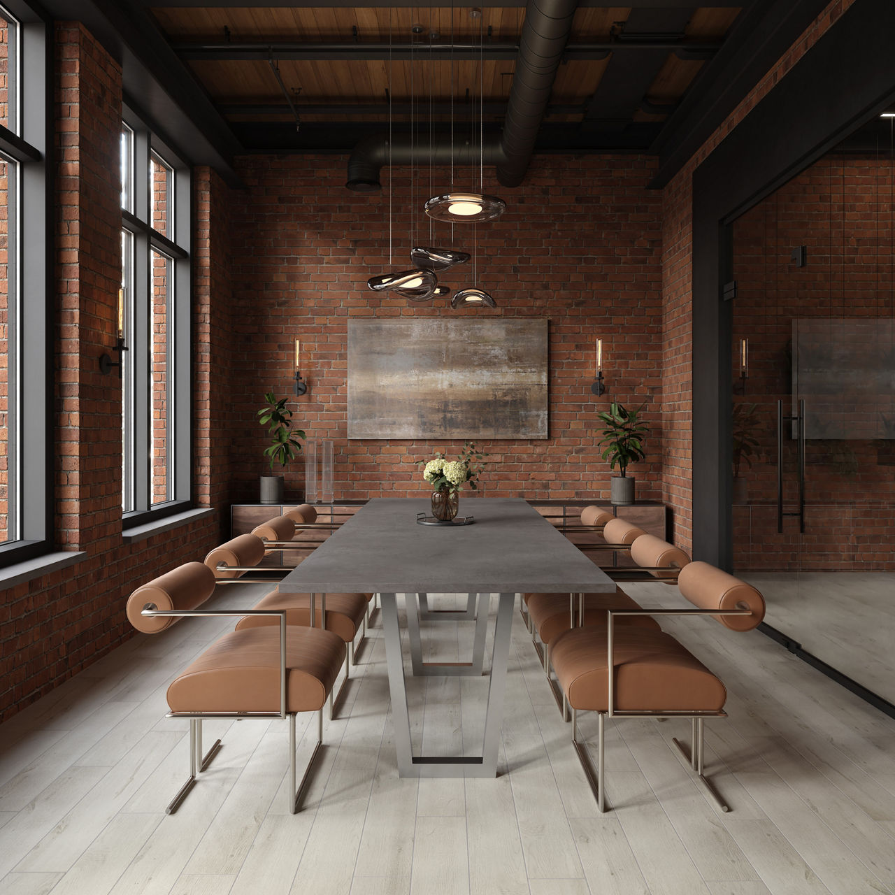 A long contemporary dining table with metal legs and tan leather chairs is arranged in a modern industrial interior. Exposed red brick walls, black-framed windows, and visible ceiling ducts emphasize the loft-style setting. Pendant lights hang above 