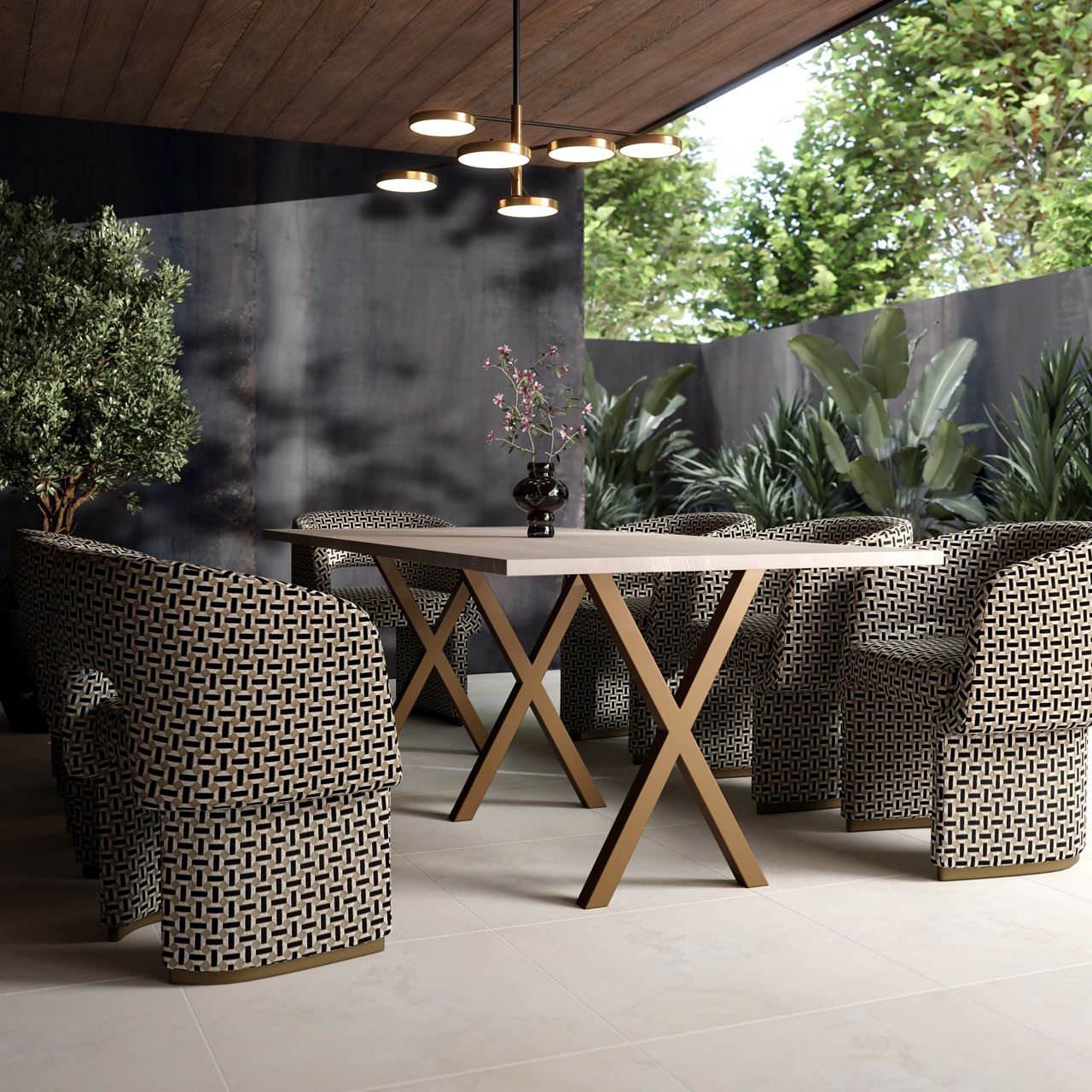 A contemporary outdoor dining space features a long rectangular table with a light tabletop and wooden X-shaped legs. Surrounding the table are several patterned woven armchairs arranged neatly for a gathering. The area is sheltered by a wooden ceili