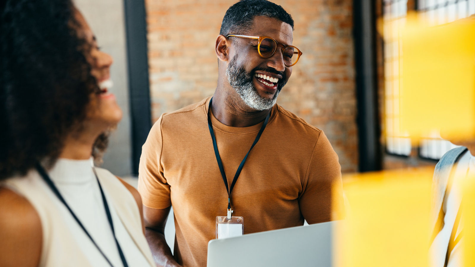 Group of cheerful professionals in a creative office setting, engaged in collaborative work on a digital device, showcasing teamwork and positive energy.