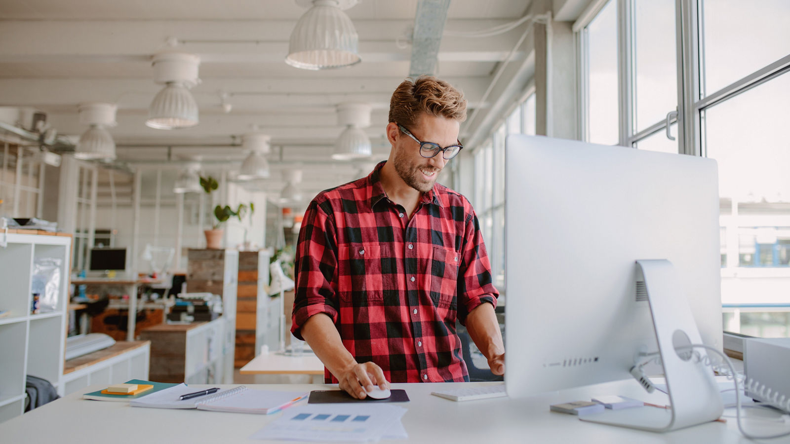 Shot of happy young man working on desktop computer in modern workplace. Young entrepreneur working at start up.