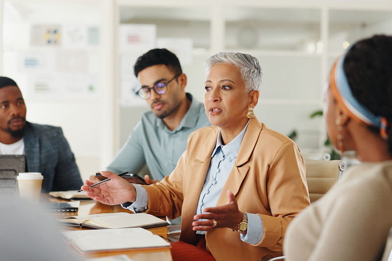 Senior, woman or business people in meeting with talking in teamwork for creative decision making. Collaboration, manager or professional employees with paperwork for project brainstorming in office.