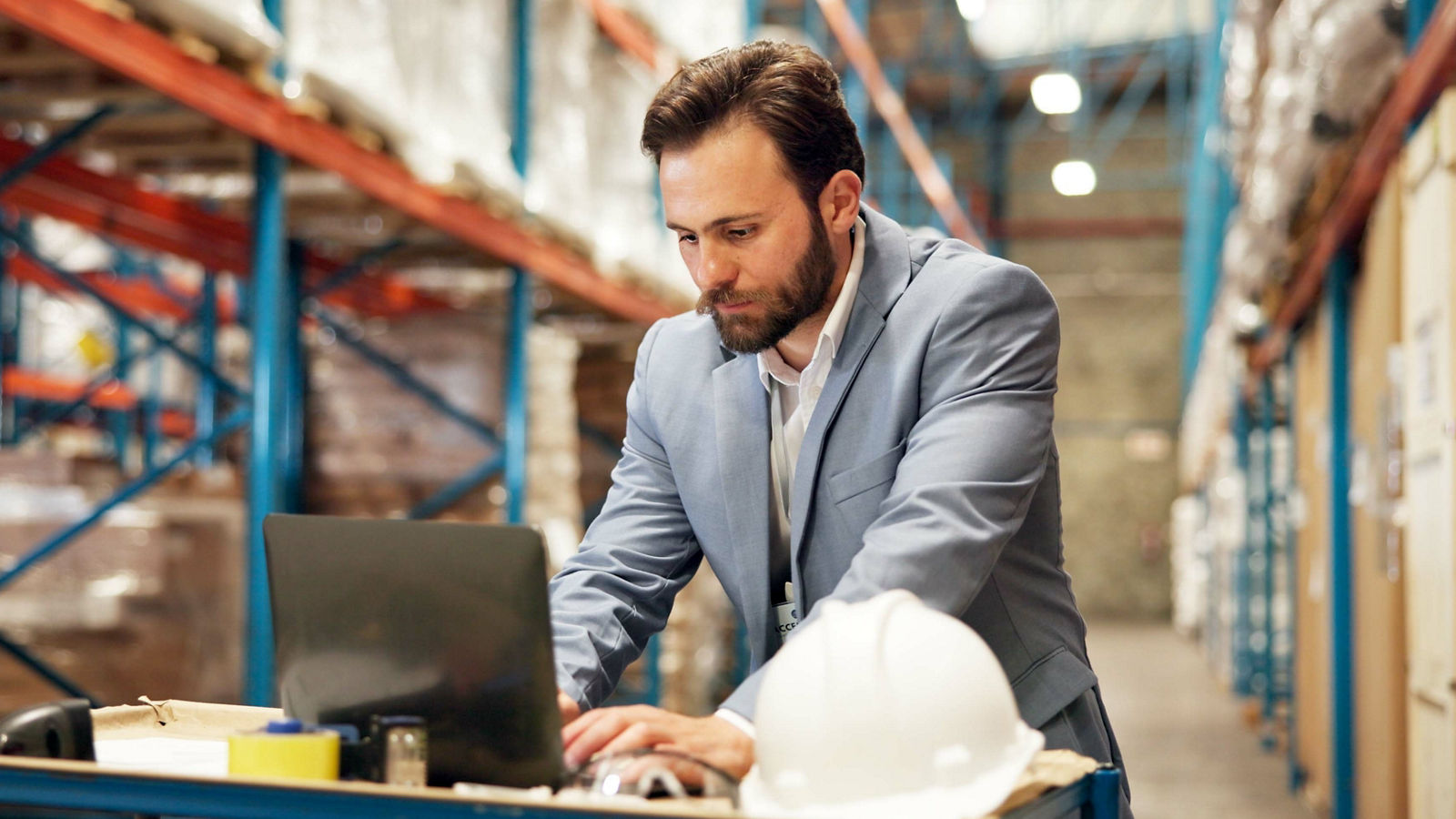 Procurement manager looking at computer in warehouse