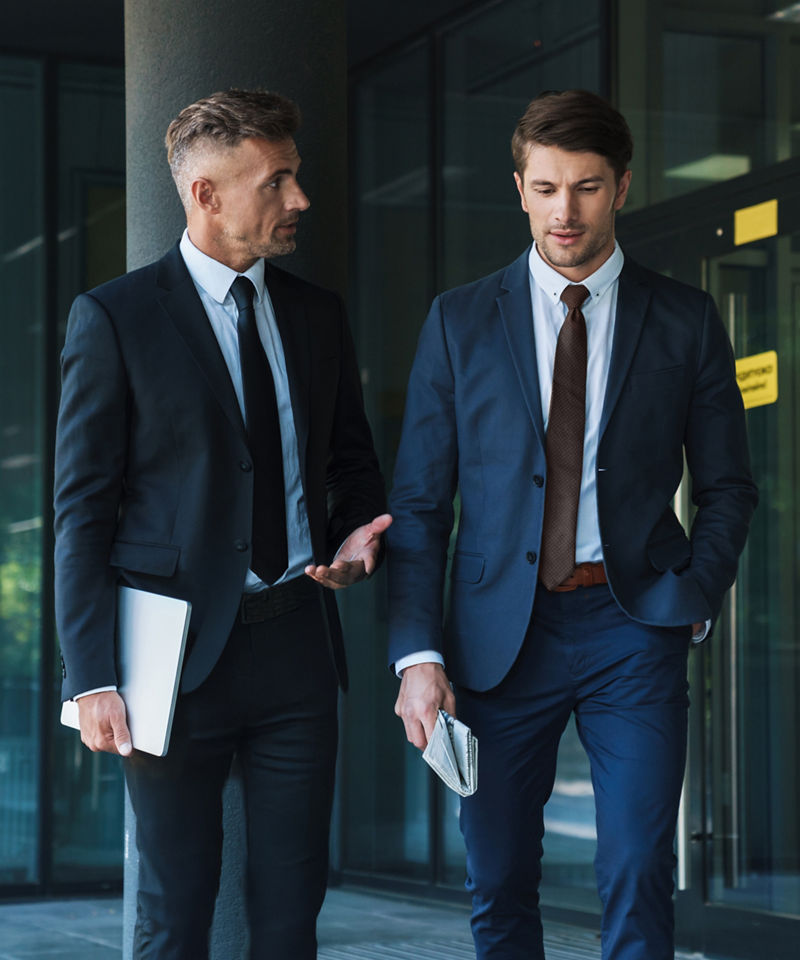 Two businessmen walking and having conversation outside of office complex