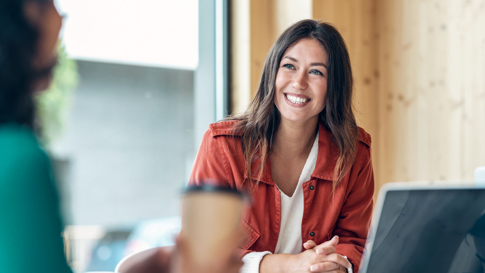 Shot of smiling young business woman listening her partner on coworking space.