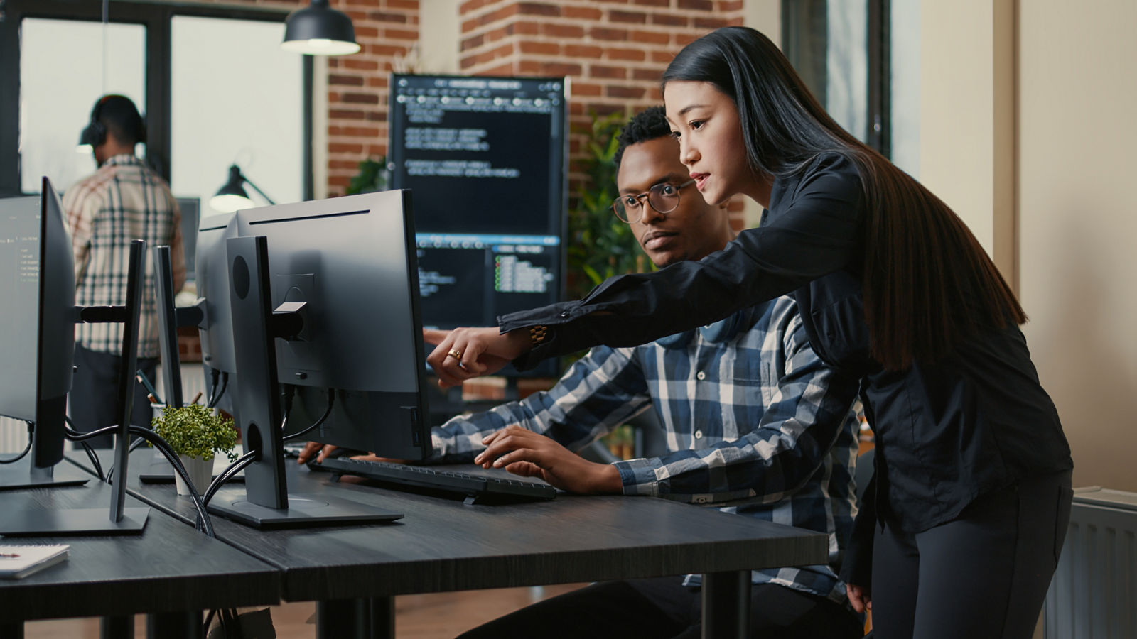 Two programers looking at computer screen with coding interface